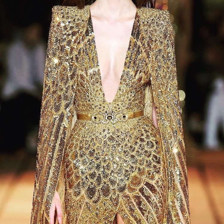 Detail of Deep V-Neck Gold Sparkling Long Gown with Padded Shoulder Cape.